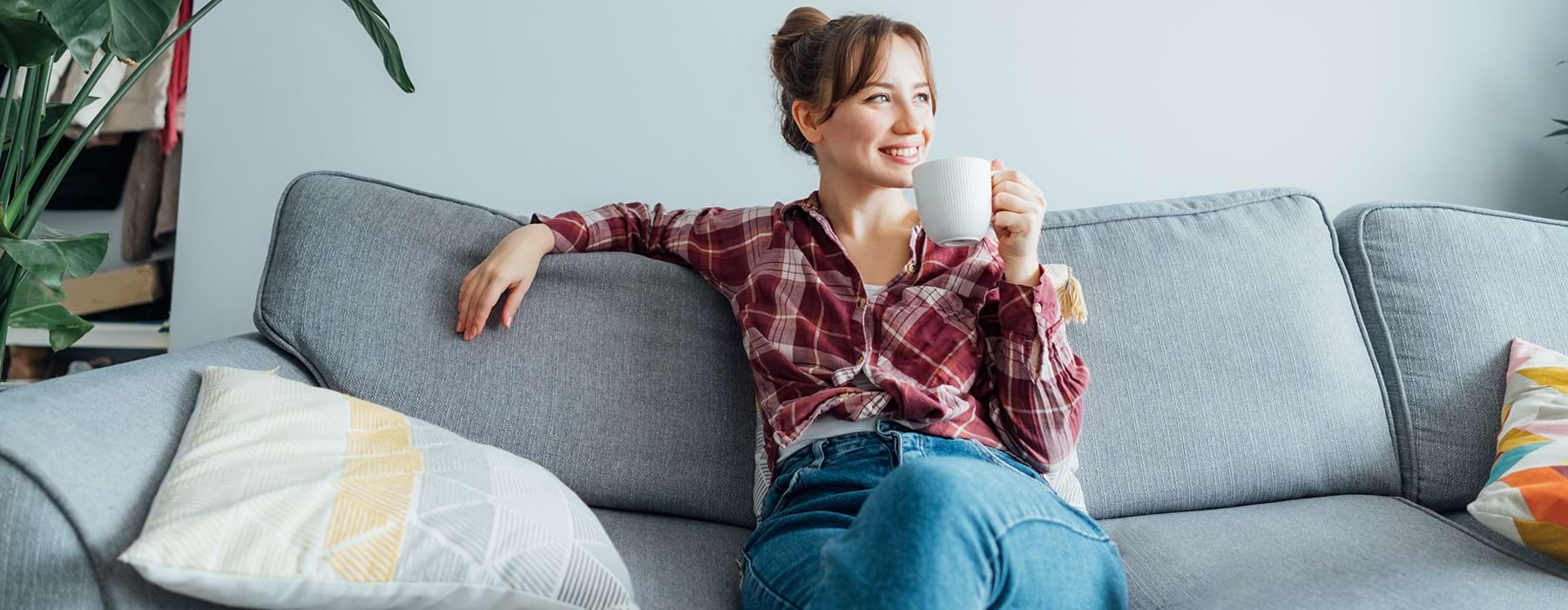 Woman sitting on her couch drinking coffee